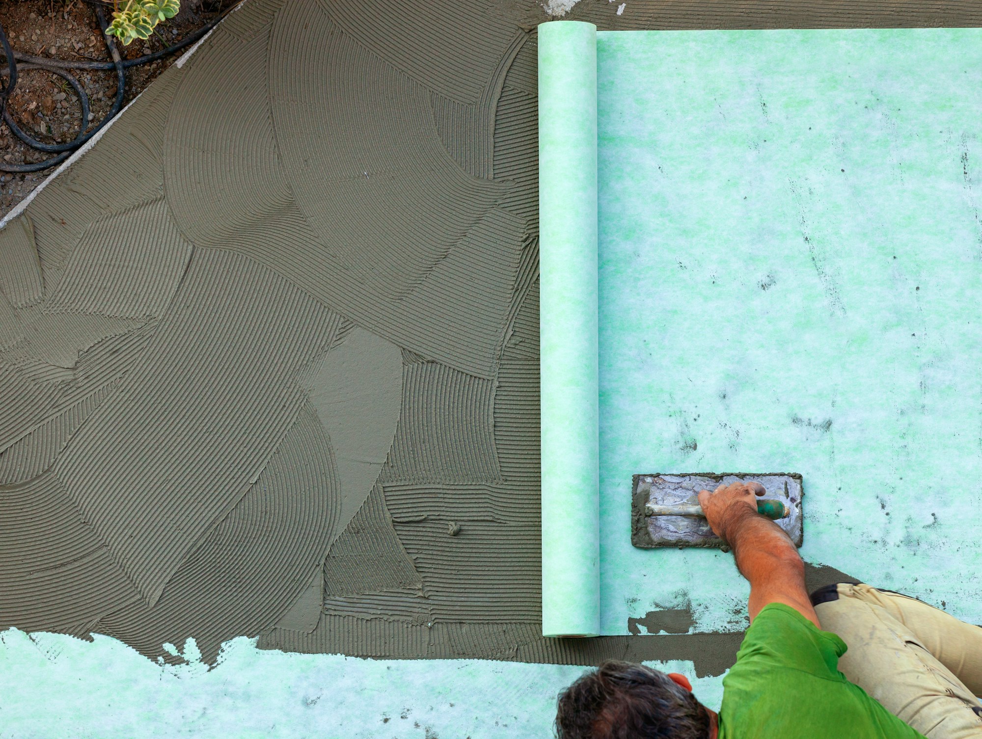Laying with with trowel a sound-absorbing mat on the screed.